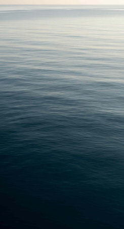 Serene ocean scene with dark blue water and gentle ripples under a pale sky
