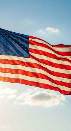 A large American flag flying with red, white, and blue colors against a clear sky