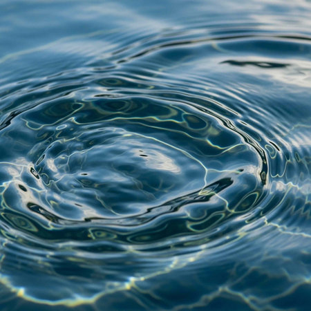 Close-up of blue water with circular ripples and shiny reflections, peaceful aquatic scene