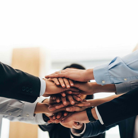 A group of diverse businesspeople stacking their hands together in a symbol of teamwork and unity in...