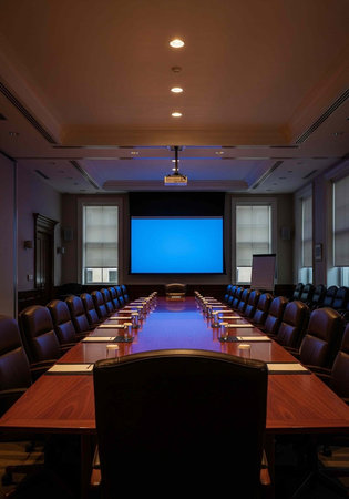 A large conference room with a long wooden table, leather chairs, and a blue screen for presentationsの写真素材