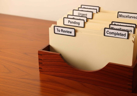 Wooden file box with labeled folders for organization and task management on a deskの写真素材