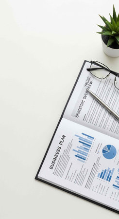 Business plan papers, glasses, and small plant on white desk, office workspace