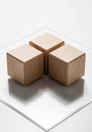 Three wooden cubes arranged on a clear glass plate with a white backgroundの写真素材