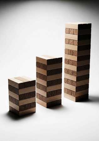 Three wooden block towers of varying heights on a white backgroundの写真素材