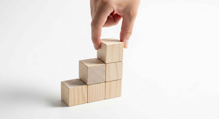 A hand placing a wooden block on top of a stack of blocks in a white background