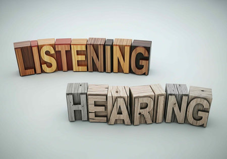 A creative arrangement of wooden blocks spelling out listening and hearing on a plain background