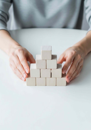 A person building a structure with wooden blocks on a white table