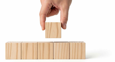 A hand holding a small wooden block above a row of stacked blocks on white background