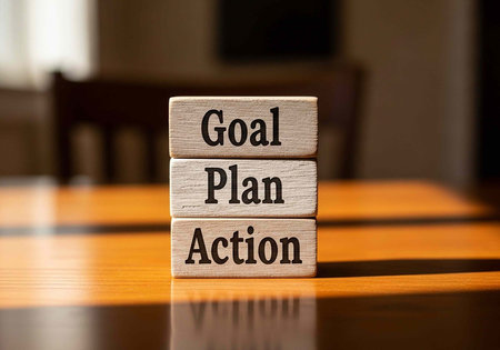 Three wooden blocks stacked with goal, plan, action text on a brown tableの写真素材