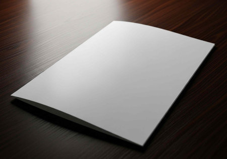 A blank white paper lies on a dark wooden table with soft lighting and shadow