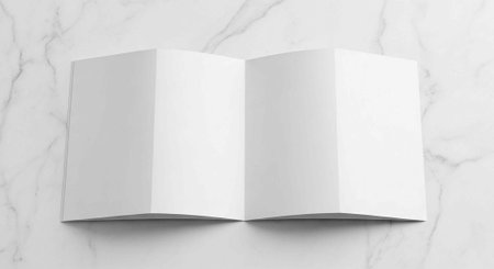 A white booklet lies open on a marble surface, showcasing blank pages and clean lines.