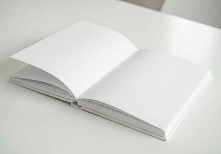An open blank book lying on a white surface with empty pages