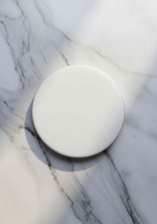 A white circular object sits on a marble surface with gray veins and shadowsの写真素材