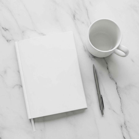 A blank notebook and pen sit on a marble desk next to a white coffee cup