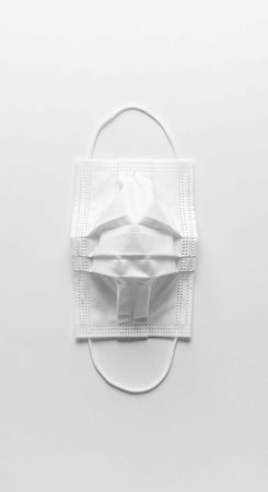 A white face mask lies on a plain surface, ready for use in a medical setting or everyday life.の写真素材