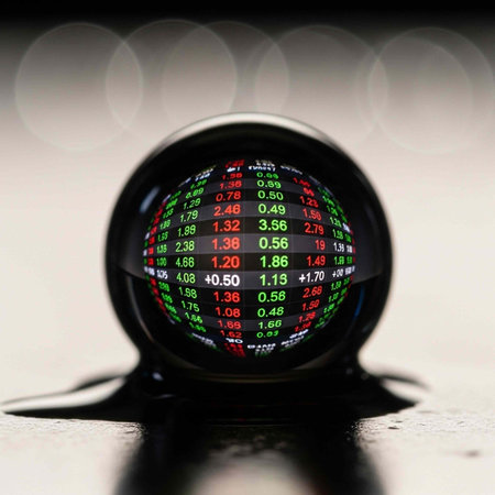 A black sphere shows green, red, and white stock market numbers on a shiny surface