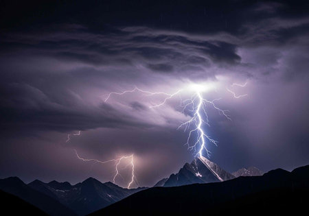 Dark mountain range under stormy night sky with lightning illuminating clouds and electric...