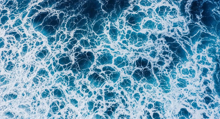 Overhead shot of turbulent ocean water with white foam and deep blue hues