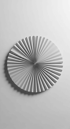 A white circular wall art piece with a pleated design casting a shadow on a plain gray backgroundの写真素材