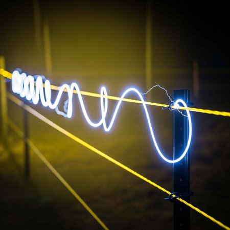 A glowing neon wire suspended between two yellow cables at night