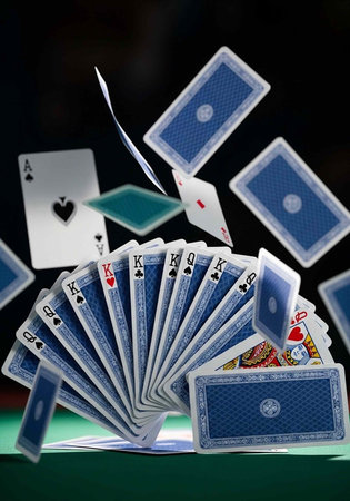 A deck of blue playing cards fanned out on a green table with cards flying through the air
