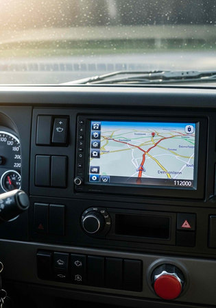 Close-up of car dashboard with GPS map, buttons, and speedometer on a wet windshield