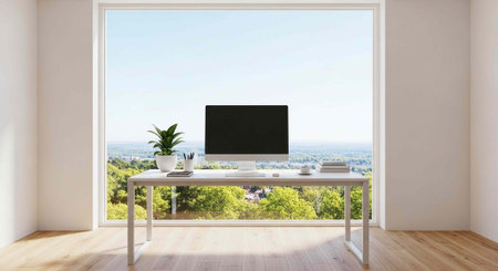 A modern office workspace with a computer and plant on a desk in front of a large window overlooking...