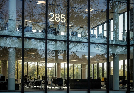 A modern office building with large windows and a tree-lined view
