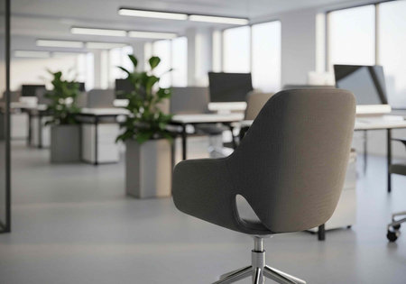 A modern office space with a comfortable chair in the foreground and desks in the background