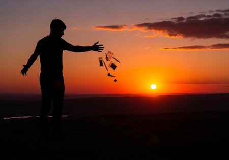 A man in silhouette throws money into the air during a vibrant sunset
