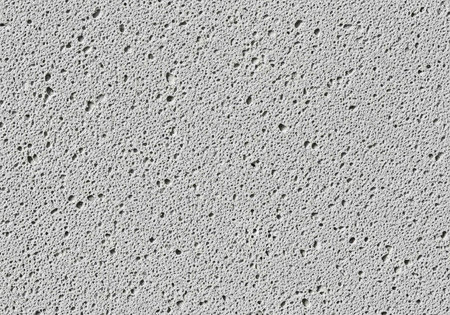 Gray surface with small black dots and tiny holes, rough texture visible