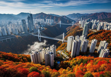 Aerial view of a modern city with a suspension bridge surrounded by vibrant autumn foliage and...