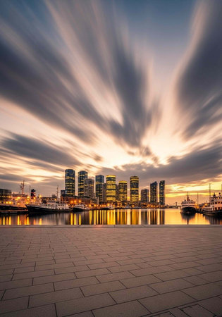 A serene cityscape at sunset with a waterfront and modern buildings under a vibrant cloudy sky