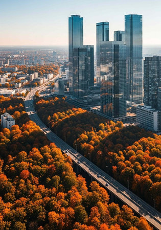 Aerial view of a modern city with skyscrapers surrounded by autumn trees and a highway