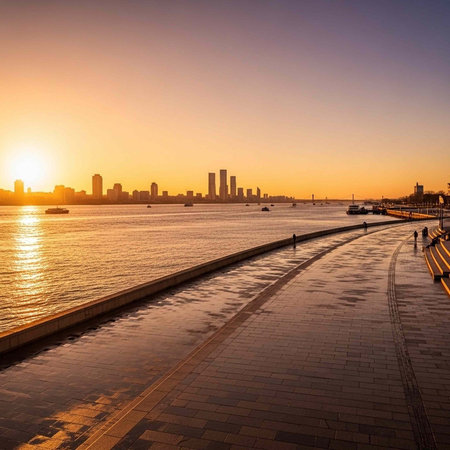 A serene waterfront promenade at sunset with a city skyline in the background and people walking...