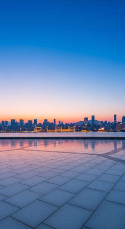 A serene cityscape at dusk with a calm body of water and a paved walkway in the foreground