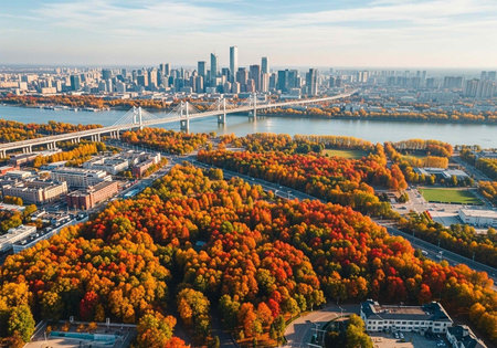 Aerial view of a city skyline with a river and vibrant autumnal trees in the foregroundの写真素材