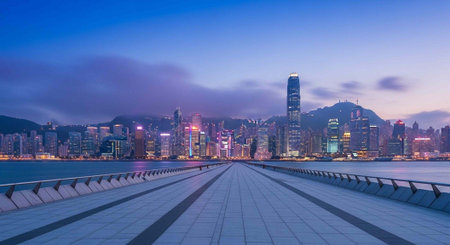 A serene cityscape at dusk with a long walkway leading to a vibrant urban skyline and mountains in the backgroundの写真素材