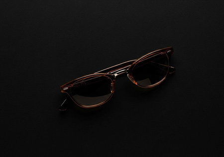 A pair of stylish glasses with dark lenses and tortoiseshell frames on a black background
