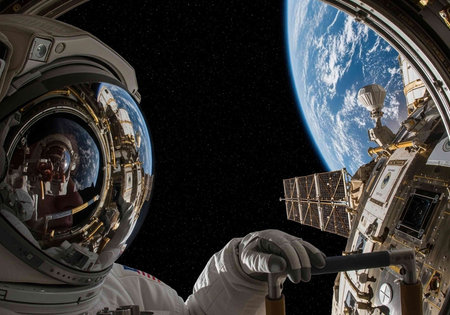 Astronaut in white space suit with reflective helmet visor near Earth and space station