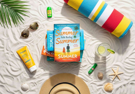 Beach items including books, sunhat, sunglasses, sunscreen, and towel on sand with seashells and starfish