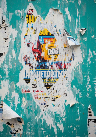 A vibrant and colorful torn poster on a teal wall with peeling paper and urban aesthetic