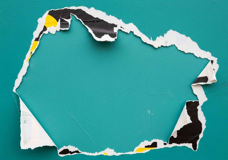 A torn piece of paper revealing a teal background with ripped edges and colorful fragments