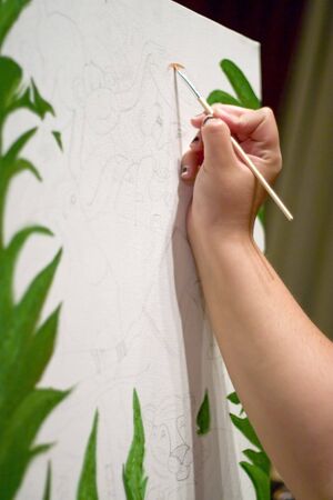 A closeup of a young woman painting on a canvas.の写真素材