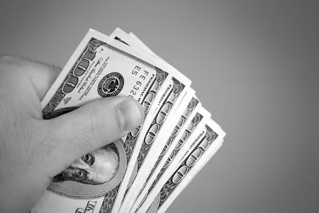 A handful of one hundred dollar bills in black and white.