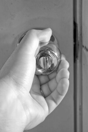A hand grasping a shiny doorknob in black and white.の写真素材