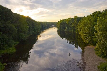 A glorious view of the Farmington River around dusk.  A patient fly fisherman is seen enjoying his hobby.の写真素材