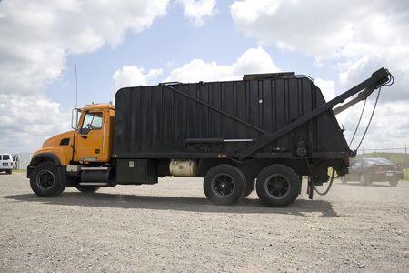 A modern garbage truck over a bright blue sky.