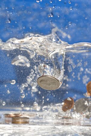 A handful of coins dropping into a pool of water.の写真素材